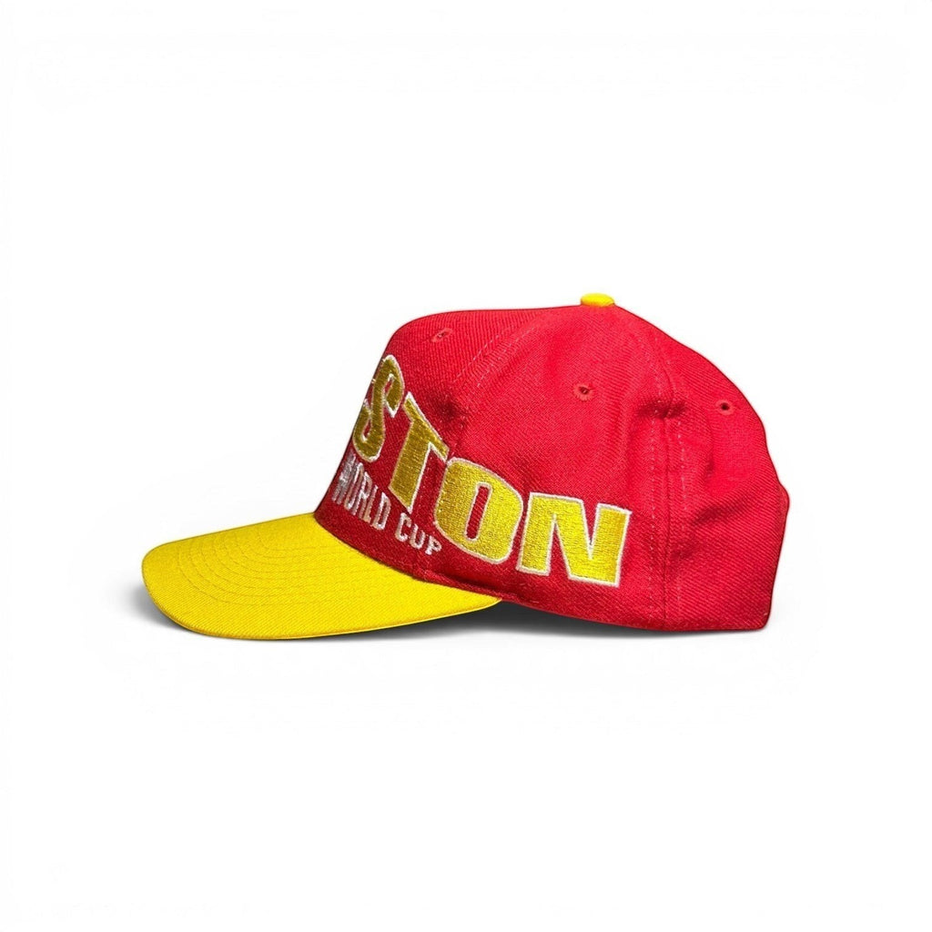ACOLDWASH red baseball cap with yellow brim and "BOSTON WORLD CUP" embroidered in gold.